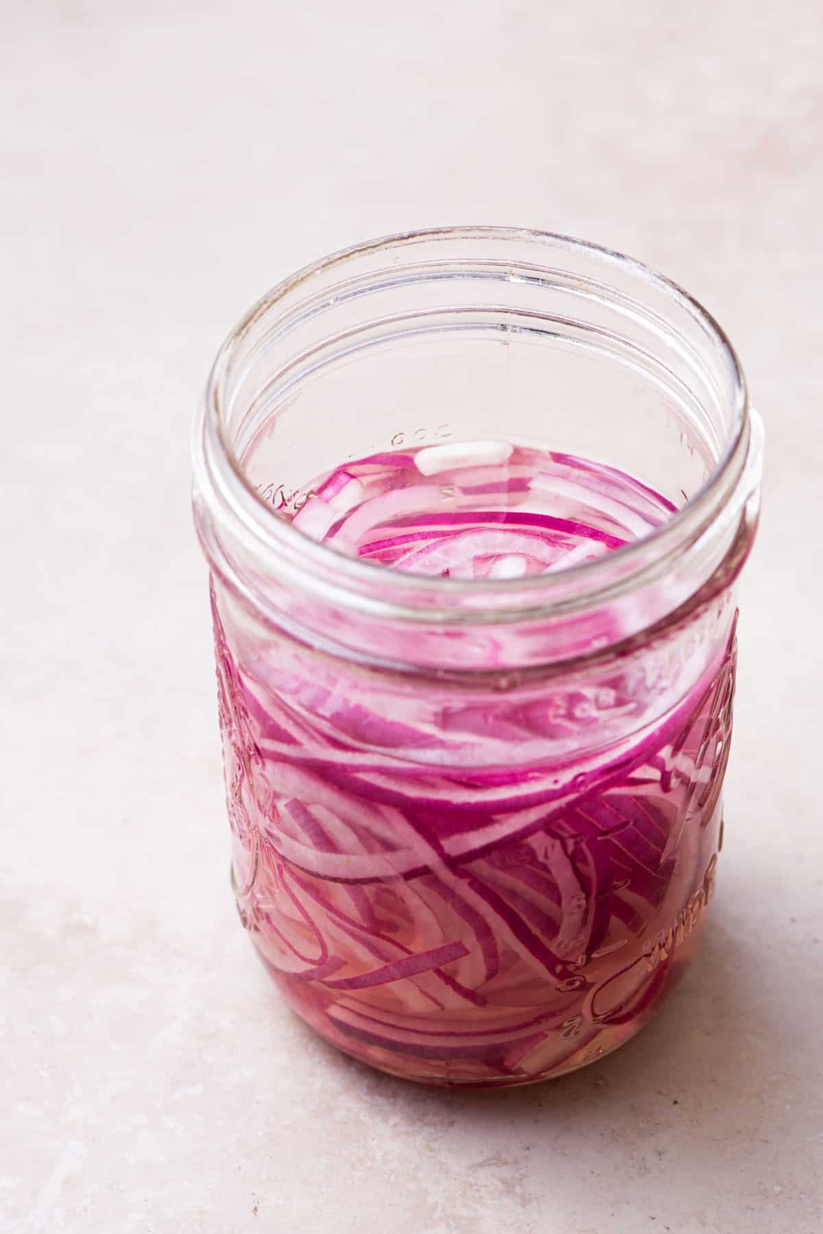 Mason jar with quick-pickled red onions.