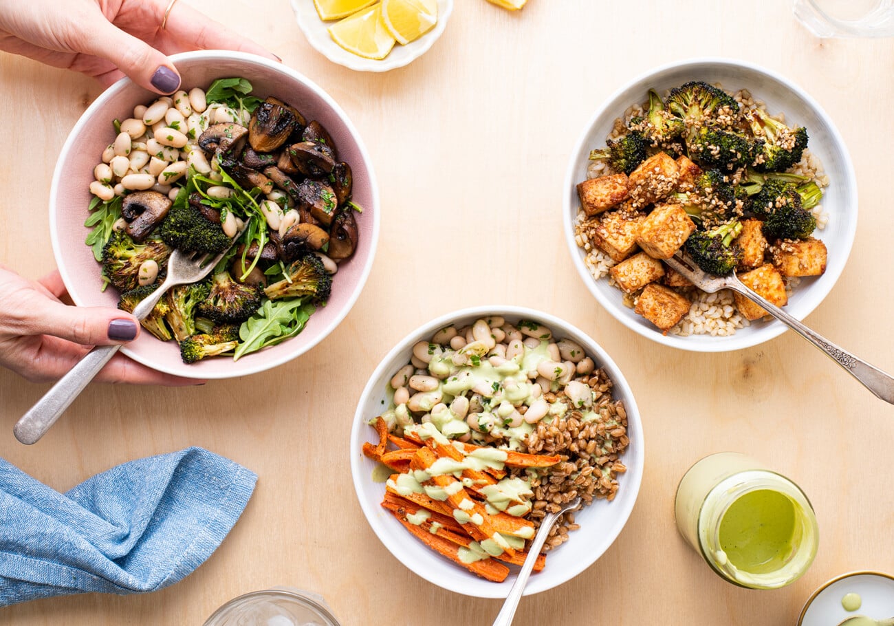 A variety of meal prep grain bowls on a wooden table.