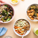 A variety of plant-based meal prepped grain bowls on a wooden table.