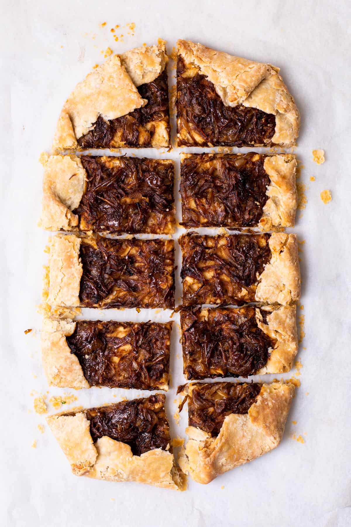 Rectangular vegan caramelized onion galette with cashew cheese on parchment paper.