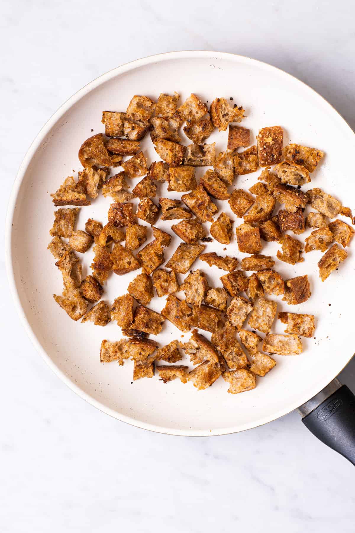 Homemade rustic croutons in a white skillet.