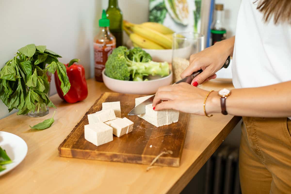 Woman's hands slicing block of tofu. Photo by Lanna Apisukh.