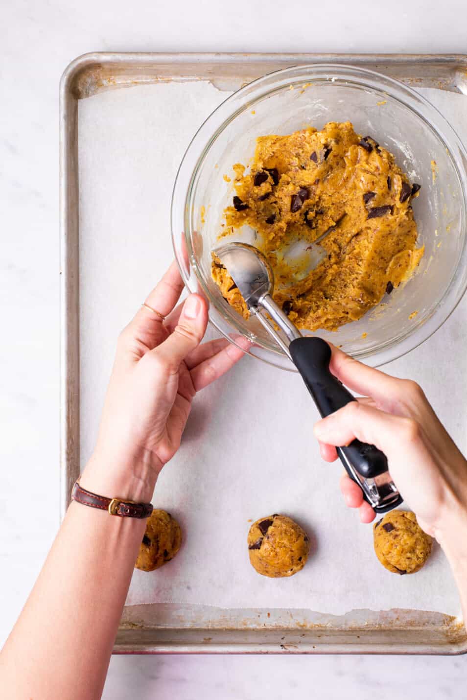 Woman's hands scooping chickpea flour cookie dough onto a baking sheet.