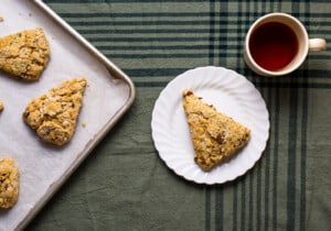 Savory vegan scones with sun-dried tomatoes on a white plate next to tea on a green tablecloth.