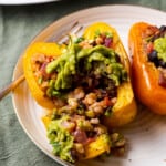 Vegan Mexican stuffed peppers with rice and beans, topped with guacamole.