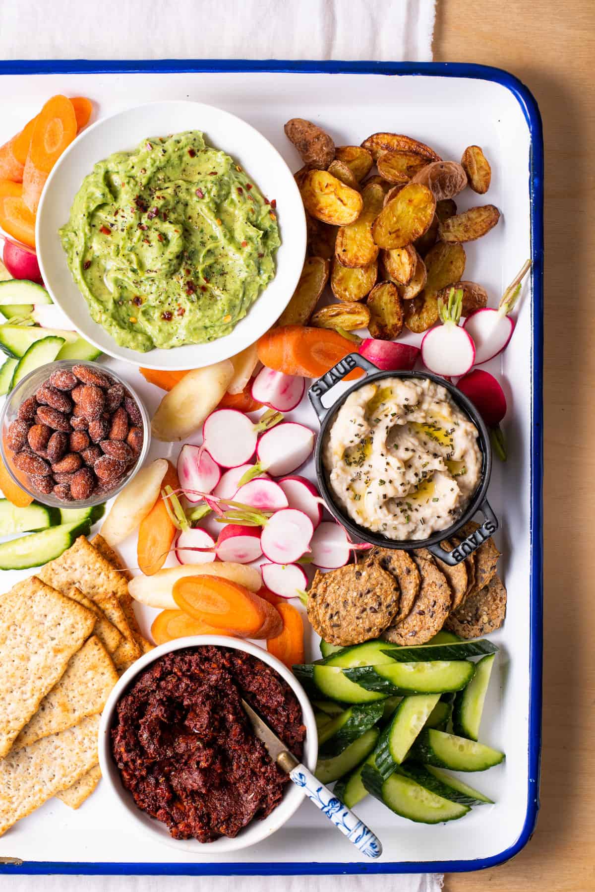 A vegan snack board with dips, crudités, and crackers.