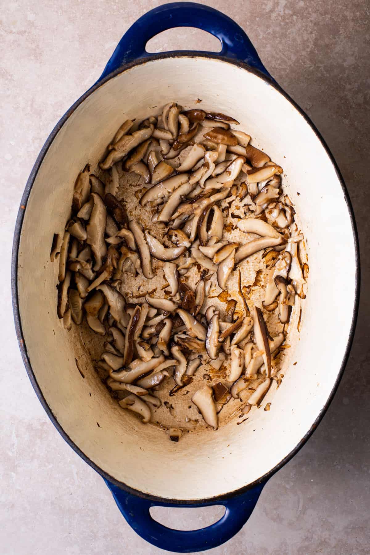 Sauteed sliced shiitakes in a Dutch oven.