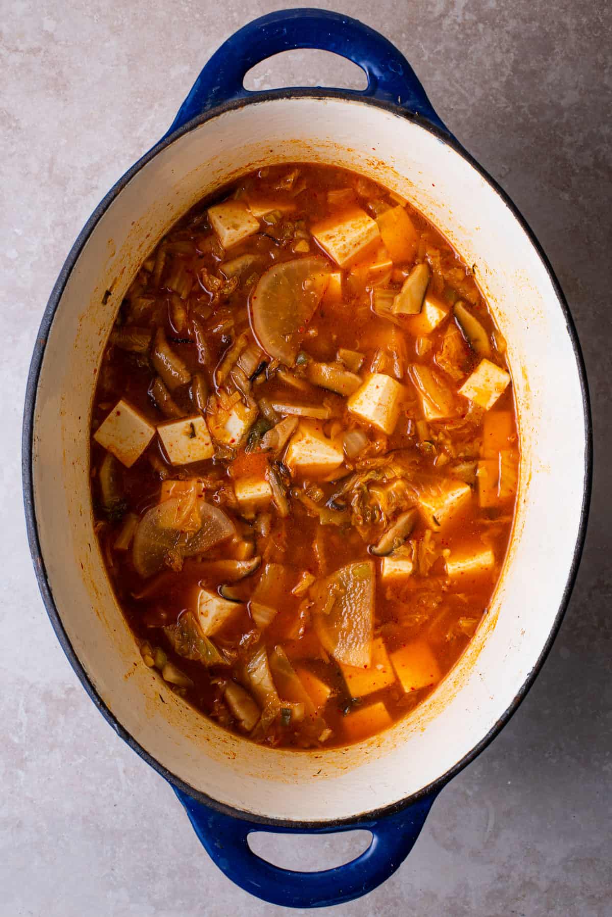 Tofu kimchi stew in an oval Dutch oven.