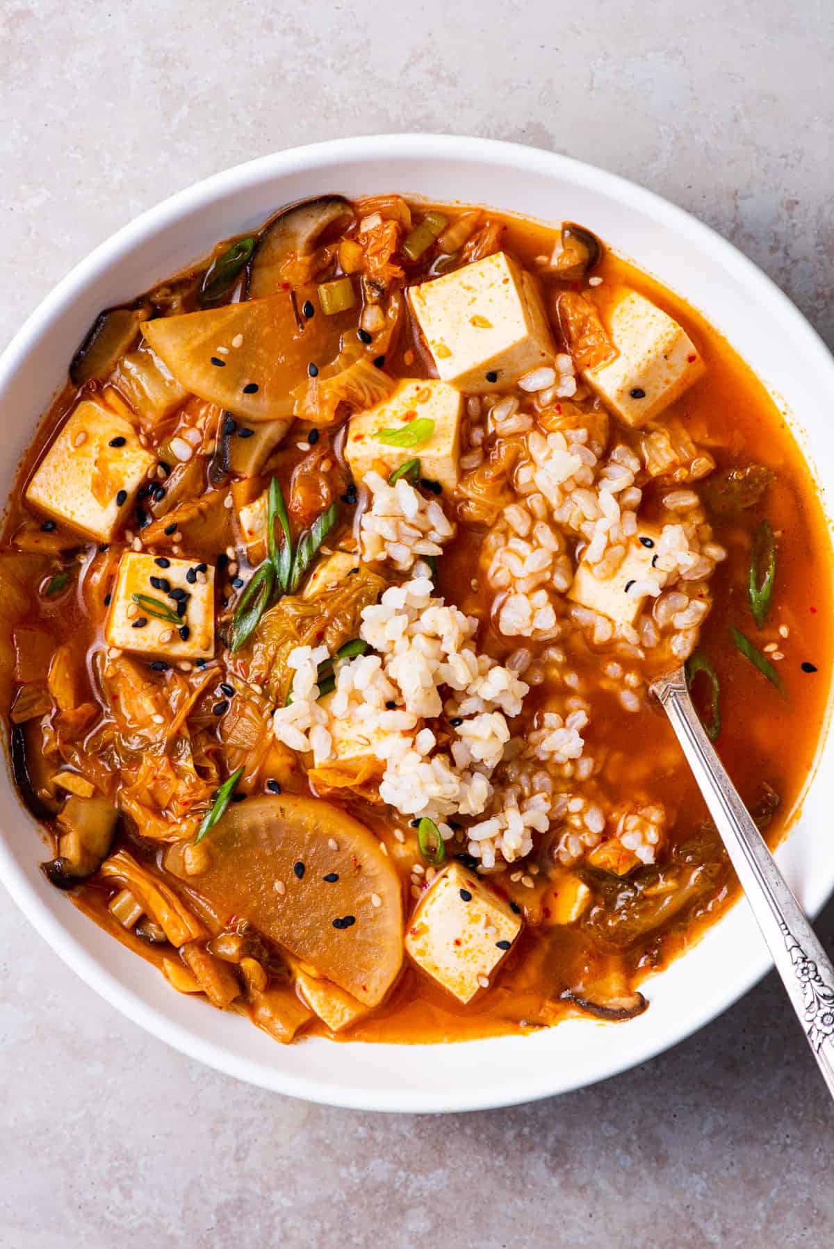 Vegan tofu kimchi soup with daikon, served with brown rice and scallions.