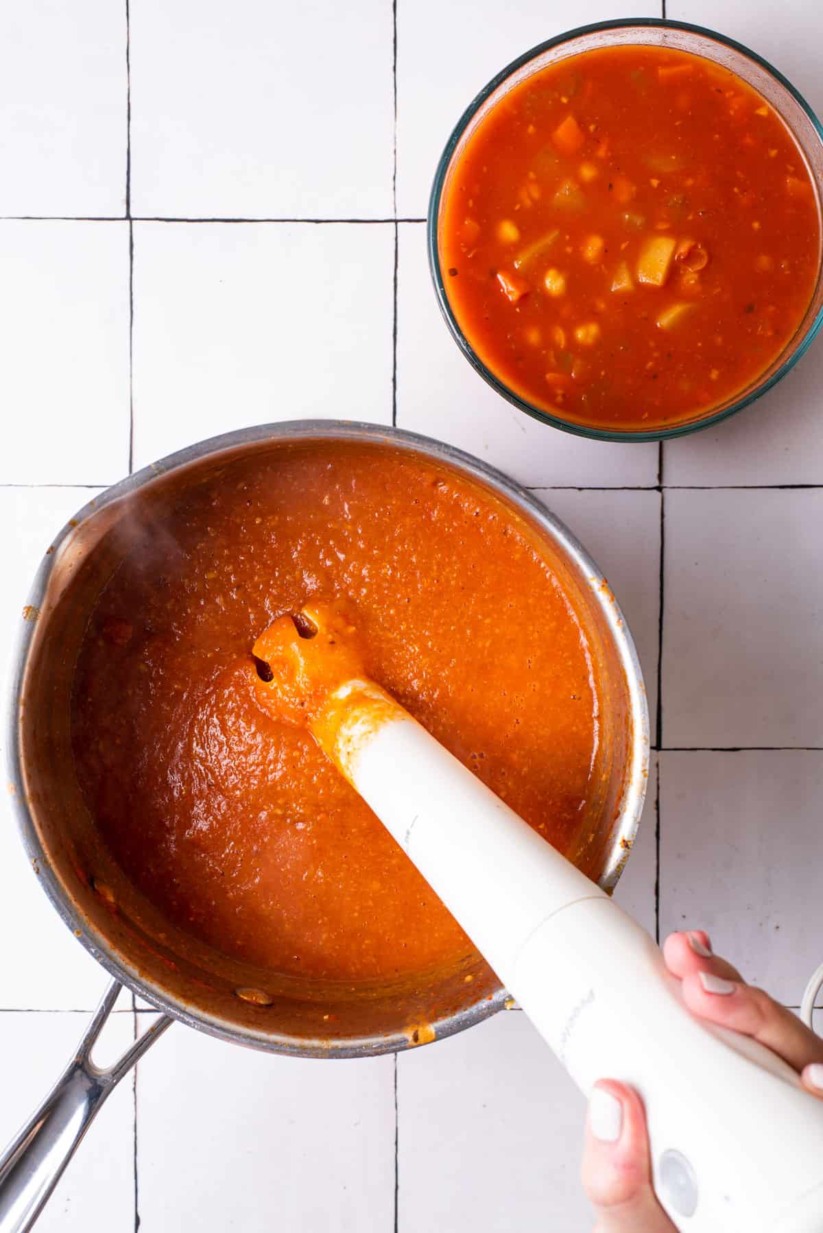 Blending tomato chickpea soup with an immersion blender.