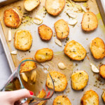 Pouring broth into a sheet pan with roasted potatoes.