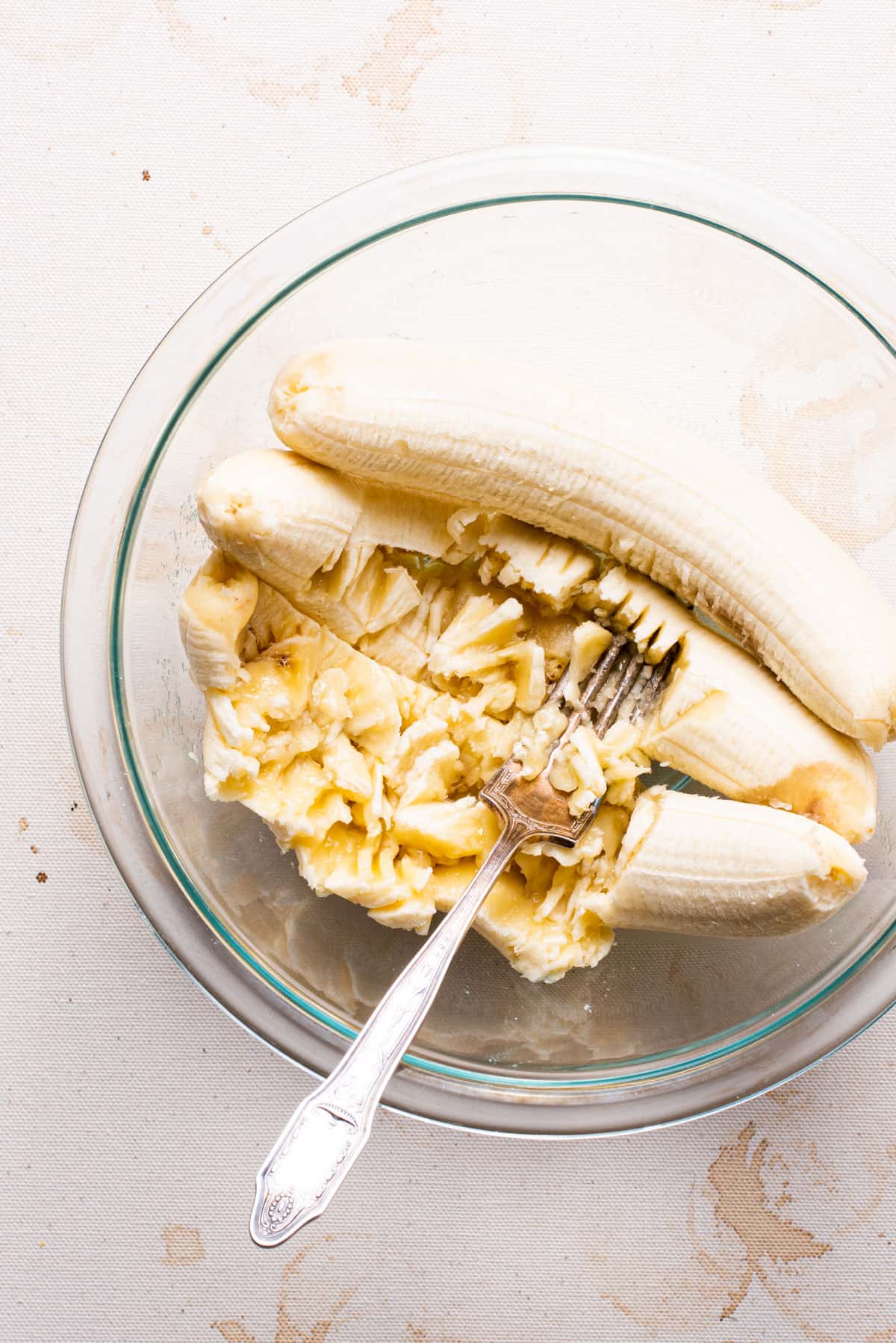 Bananas mashed in a bowl with a fork.