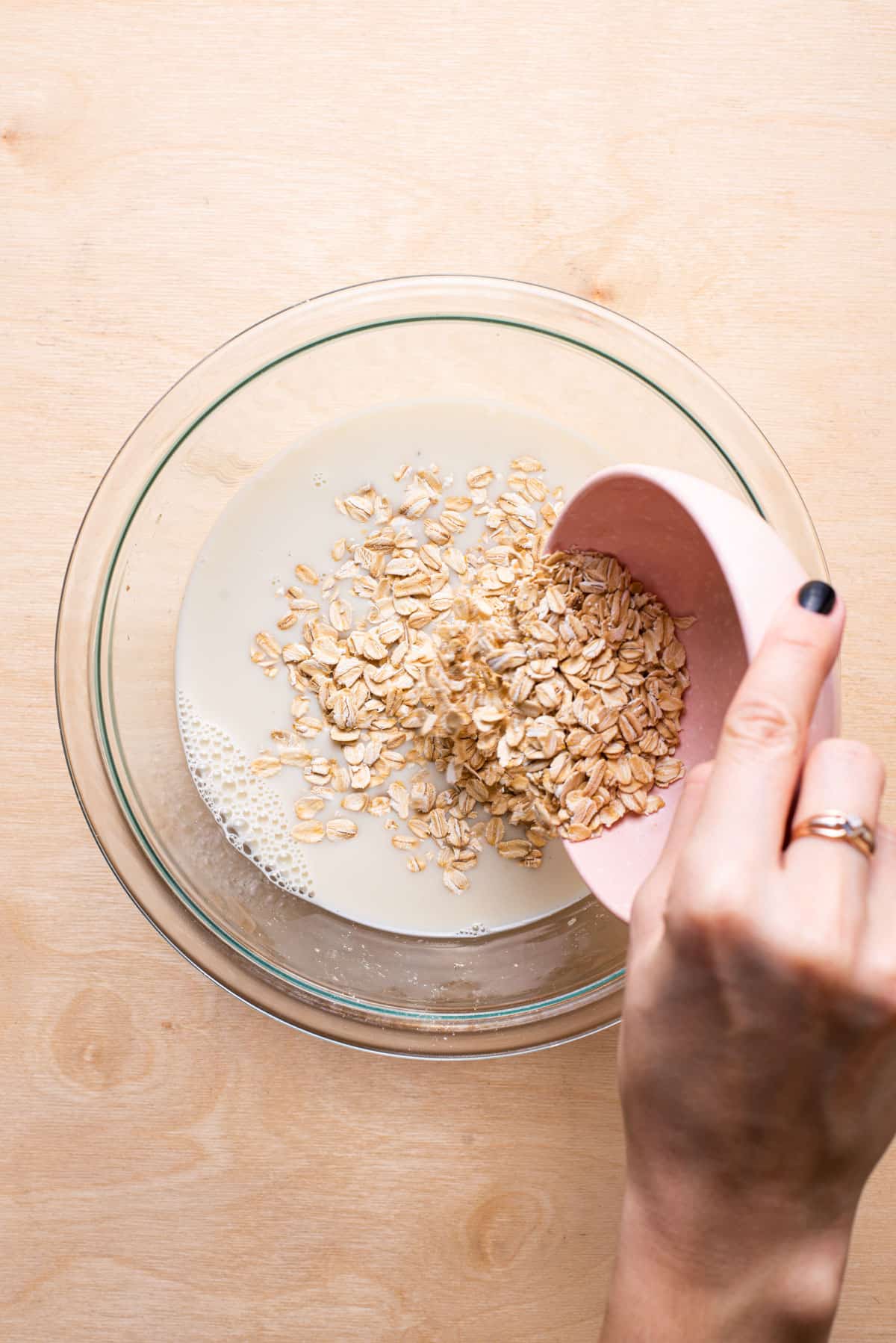 Adding oats to a bowl with milk.
