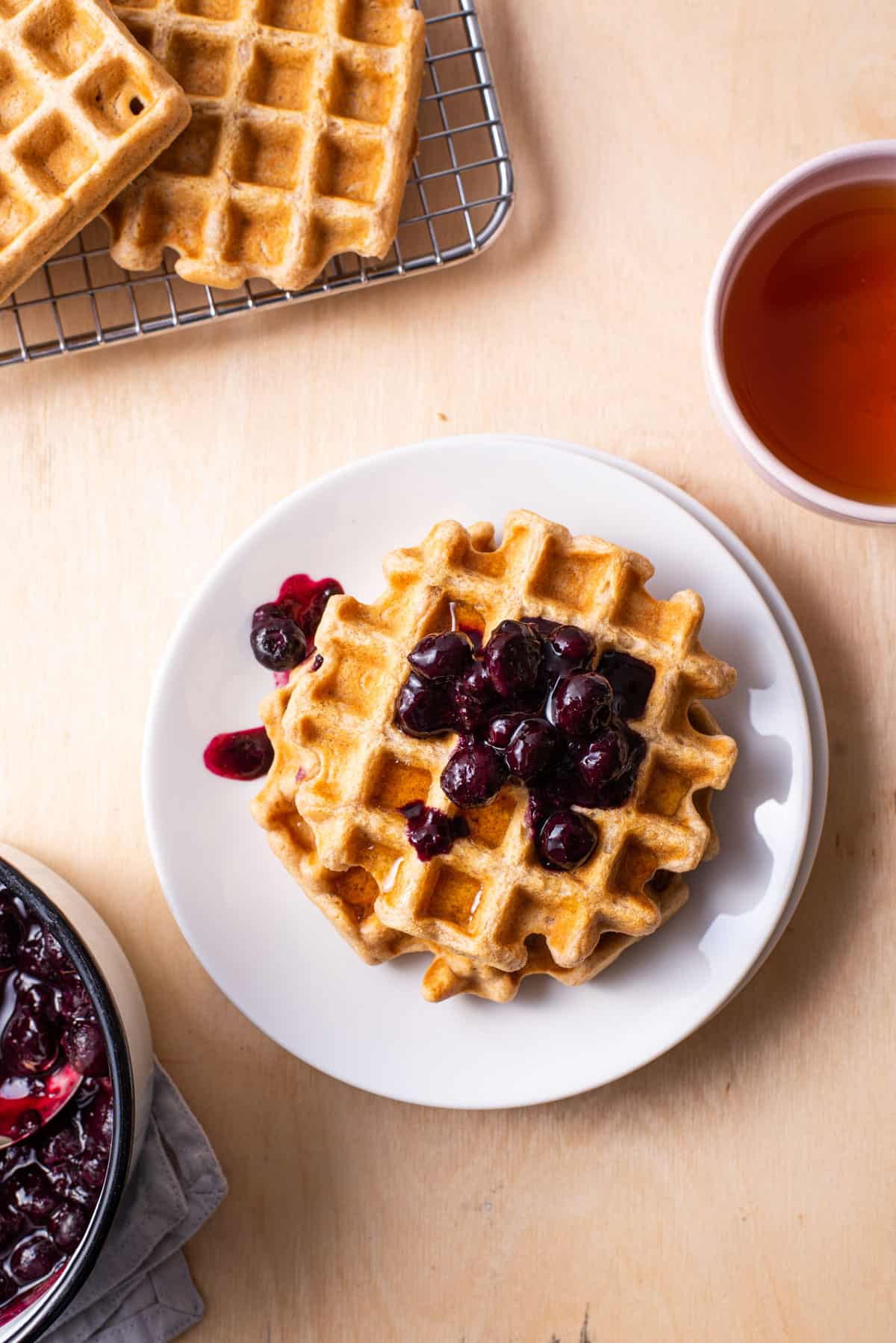 Vegan oat waffles on a white plate with blueberry compote.