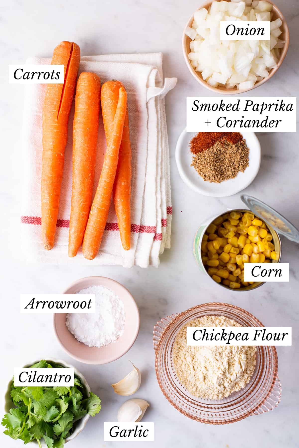 Ingredients gathered to make carrot corn fritters on a marble table.