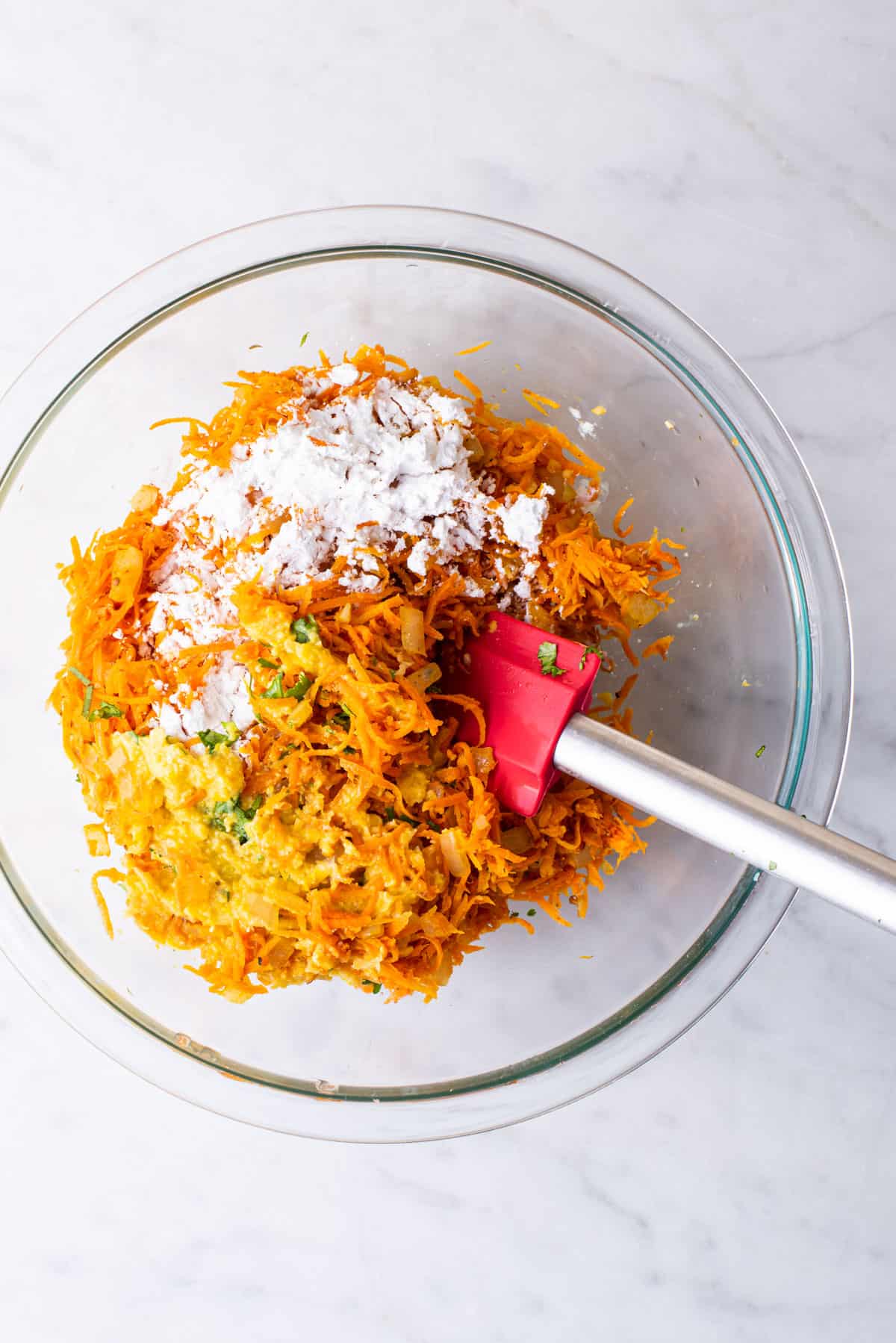 Mixture of grated carrots, pureed corn, flour, and spices in a bowl.