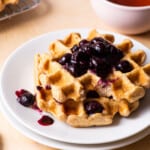 Vegan oat waffles topped with blueberry compote on a white plate.