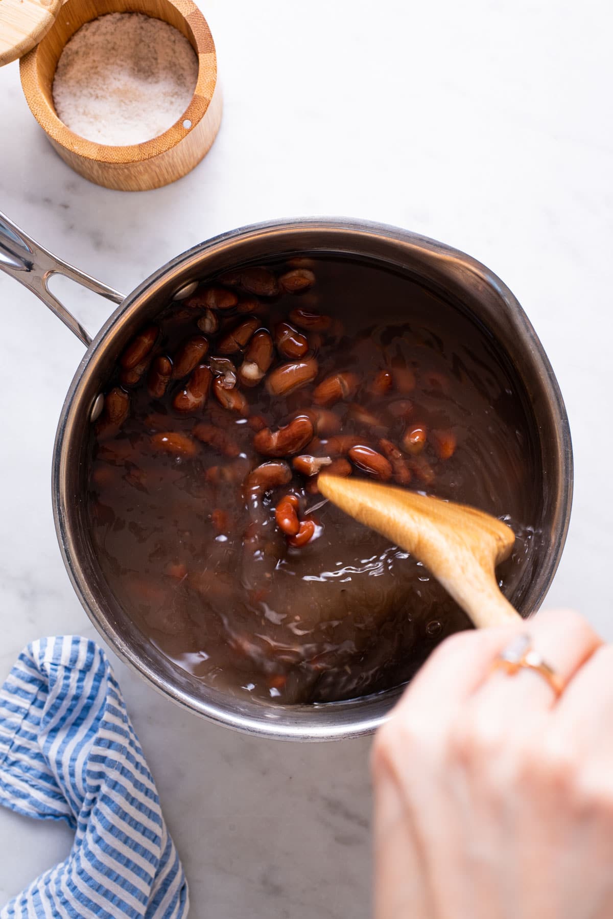 Stirring salt into a pot of cooked kidney beans.