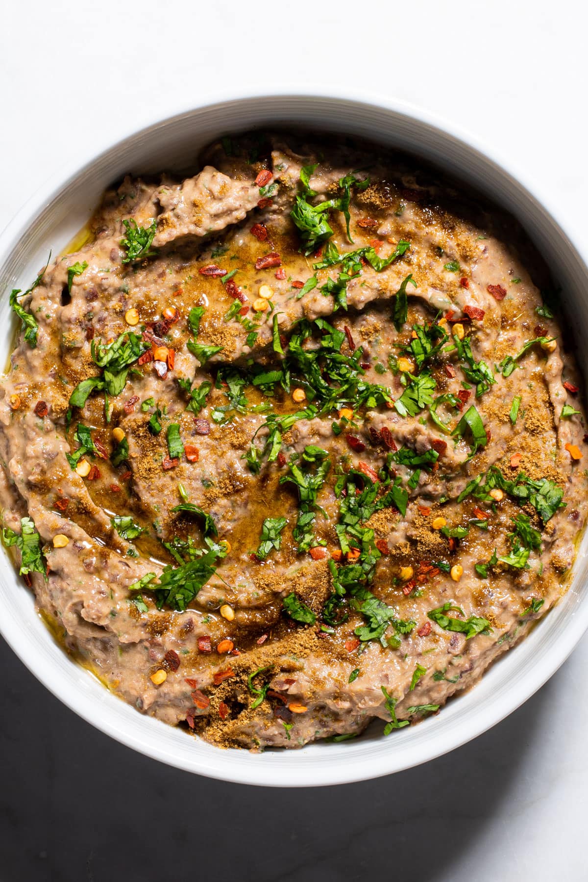 Creamy Mexican black bean dip in a white bowl, sprinkled with cilantro.