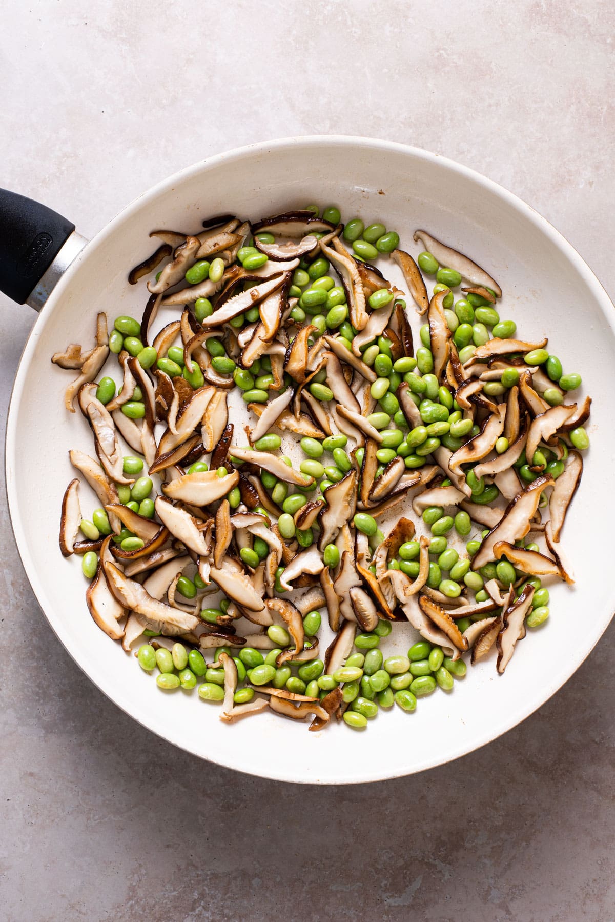 Sauteed shiitakes and edamame in a skillet.