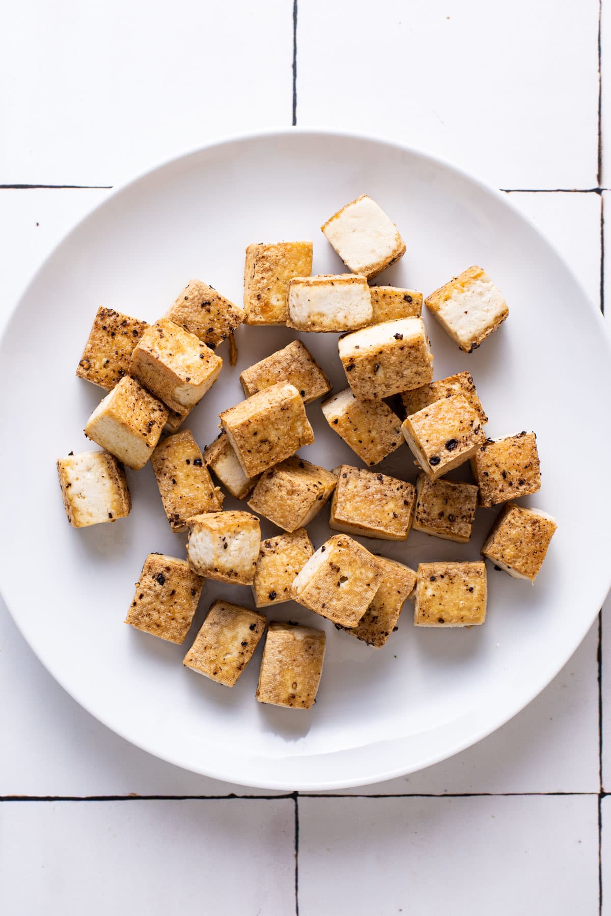 Crispy tofu cubes on a white plate.