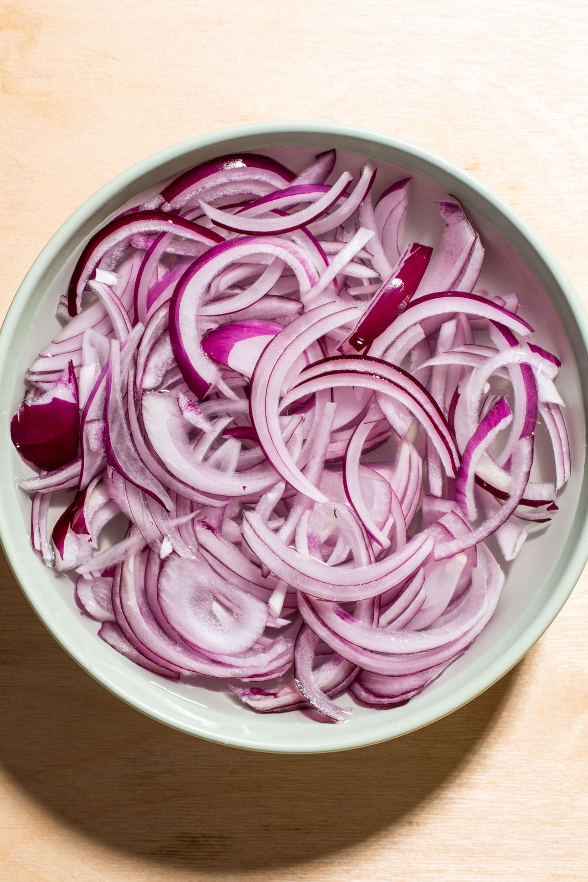 Red onions soaking in a bowl of water.