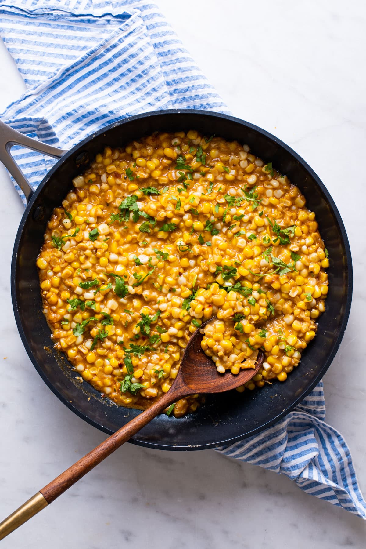 Creamed corn in a skillet garnished with cilantro.