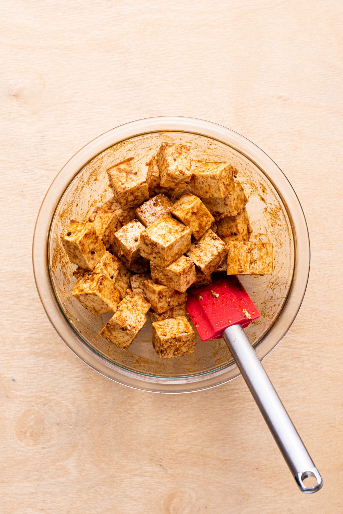Marinating tofu cubes in a glass bowl.