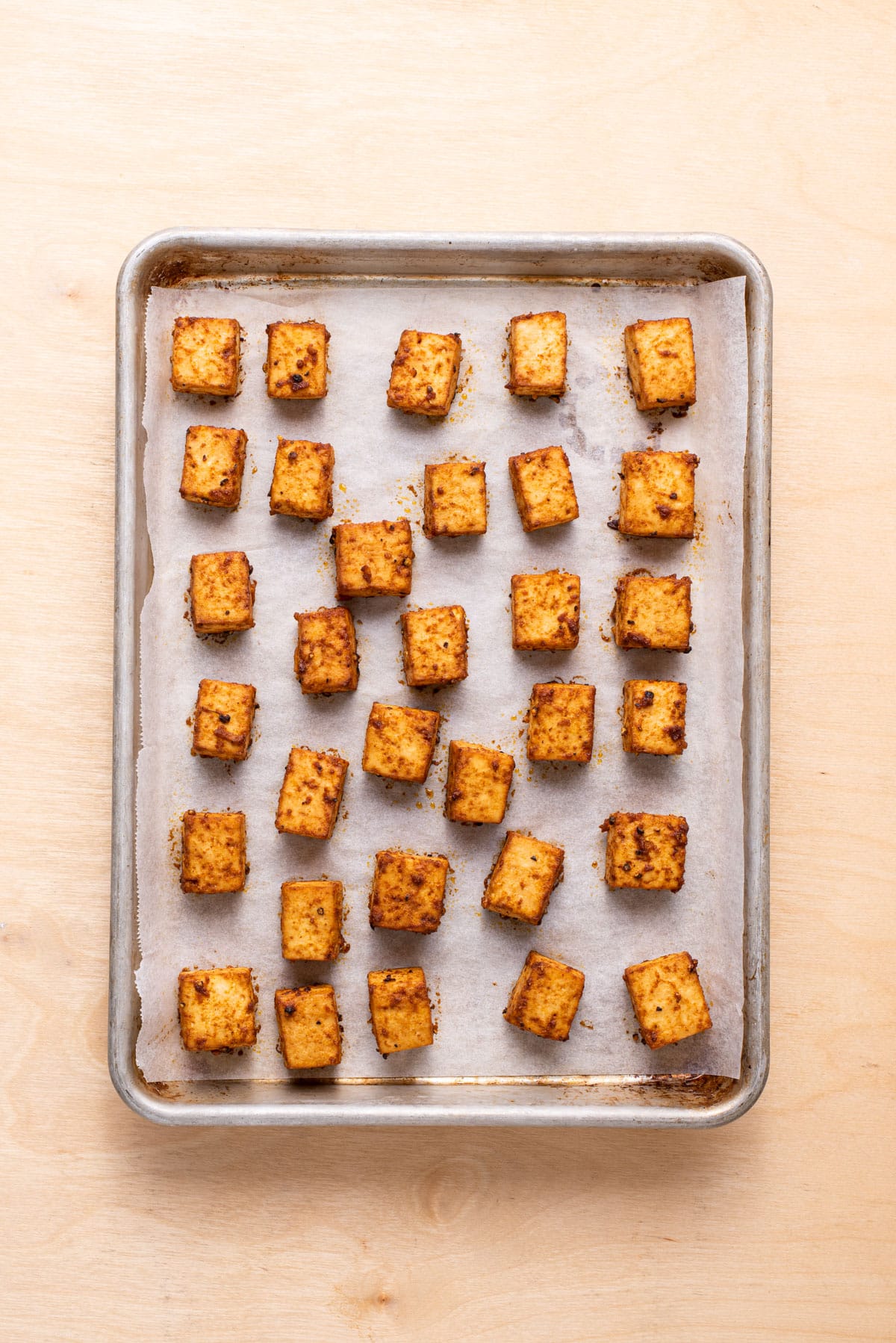 Marinated baked tofu cubes on a baking sheet.