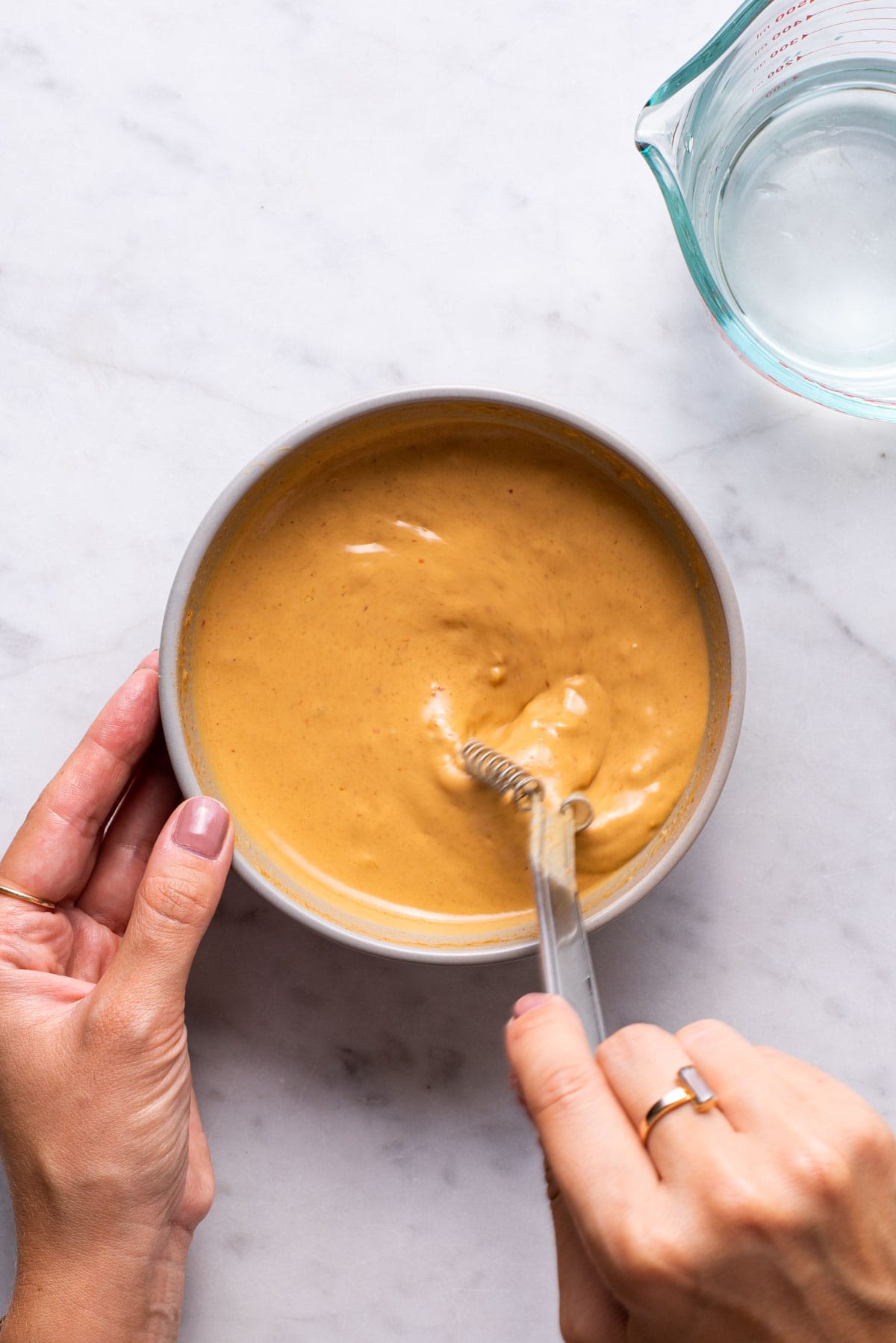 Whisking peanut sauce in a bowl.