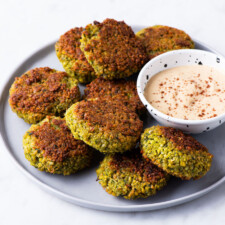 Baked falafel patties on a gray plate next to tahini sauce.