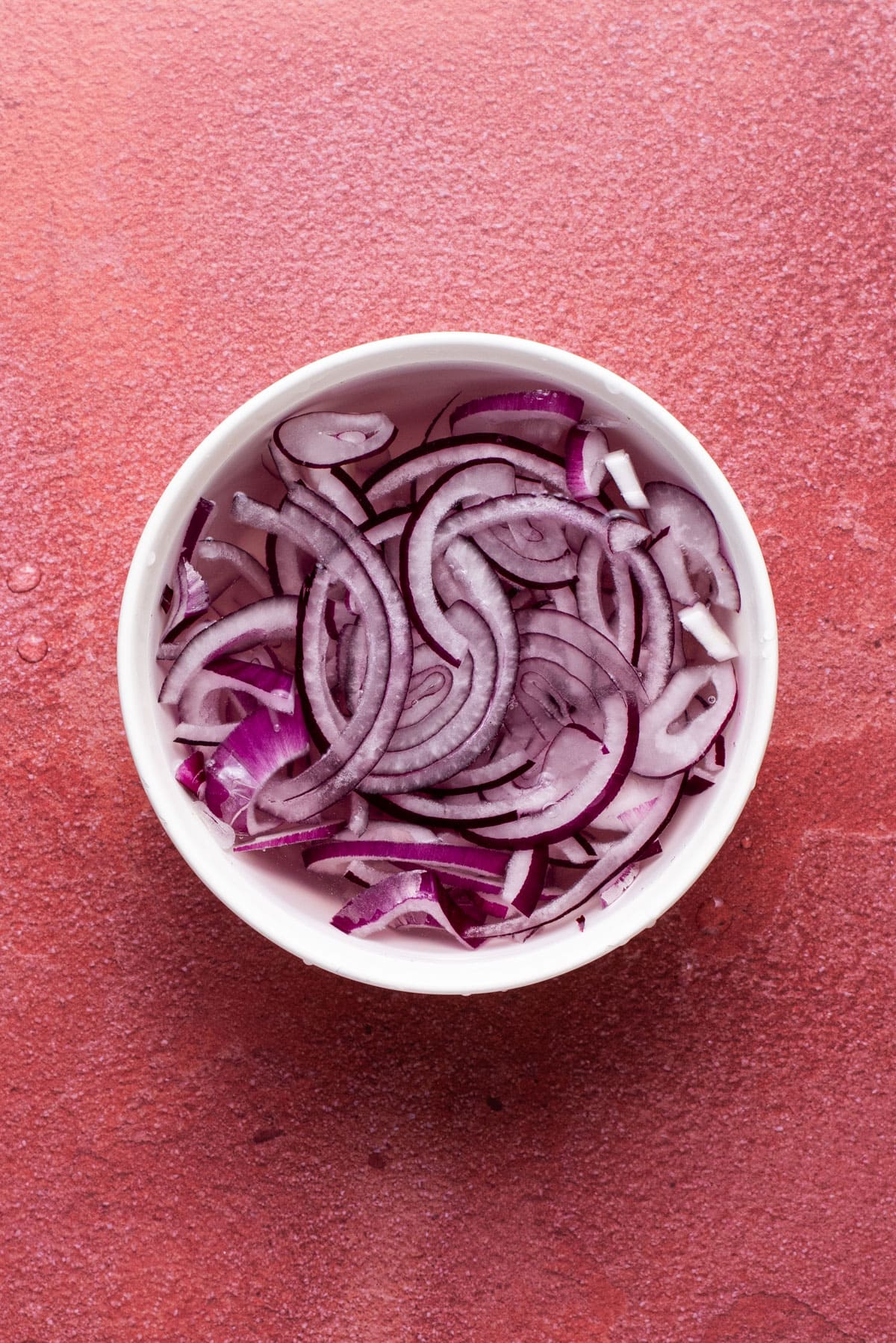Red onion soaking in a bowl of water.