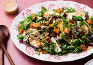 Thanksgiving arugula salad with sweet potatoes and apples on an oval platter.