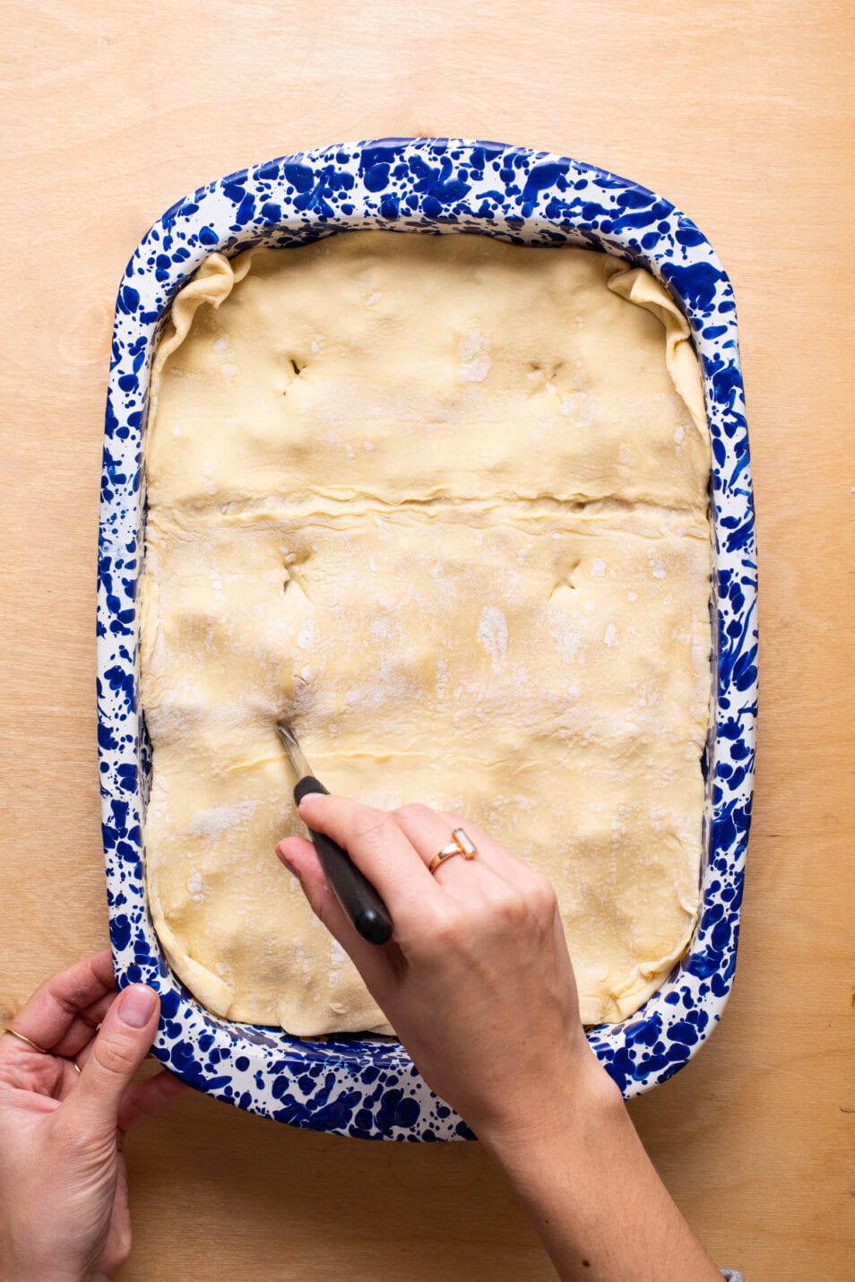 Cutting air vents into puff pastry dough on a pot pie.