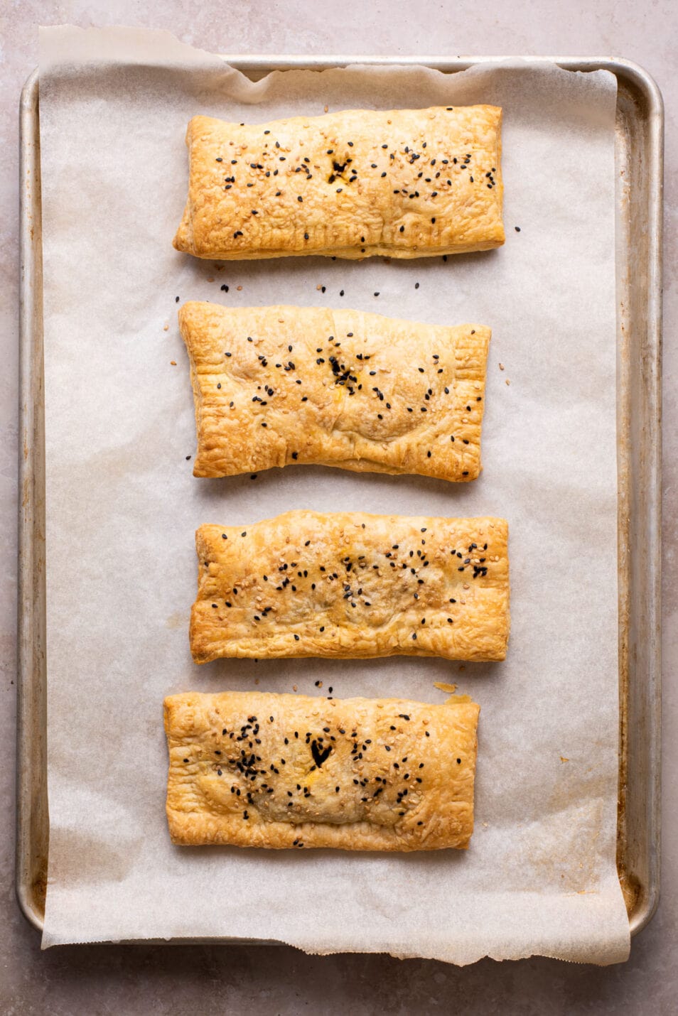 Vegan mushroom hand pies with puff pastry on a baking sheet.