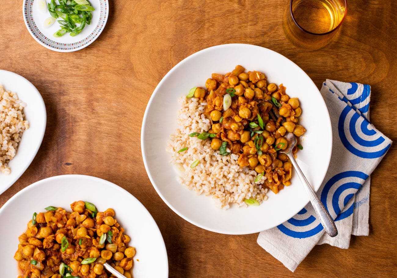 Two white bowls with chana masala and brown rice.