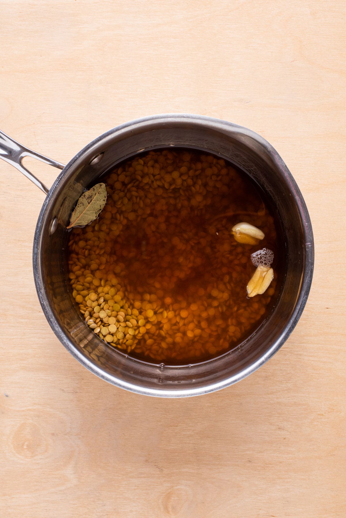 Lentils cooking in a pot with vegetable broth.
