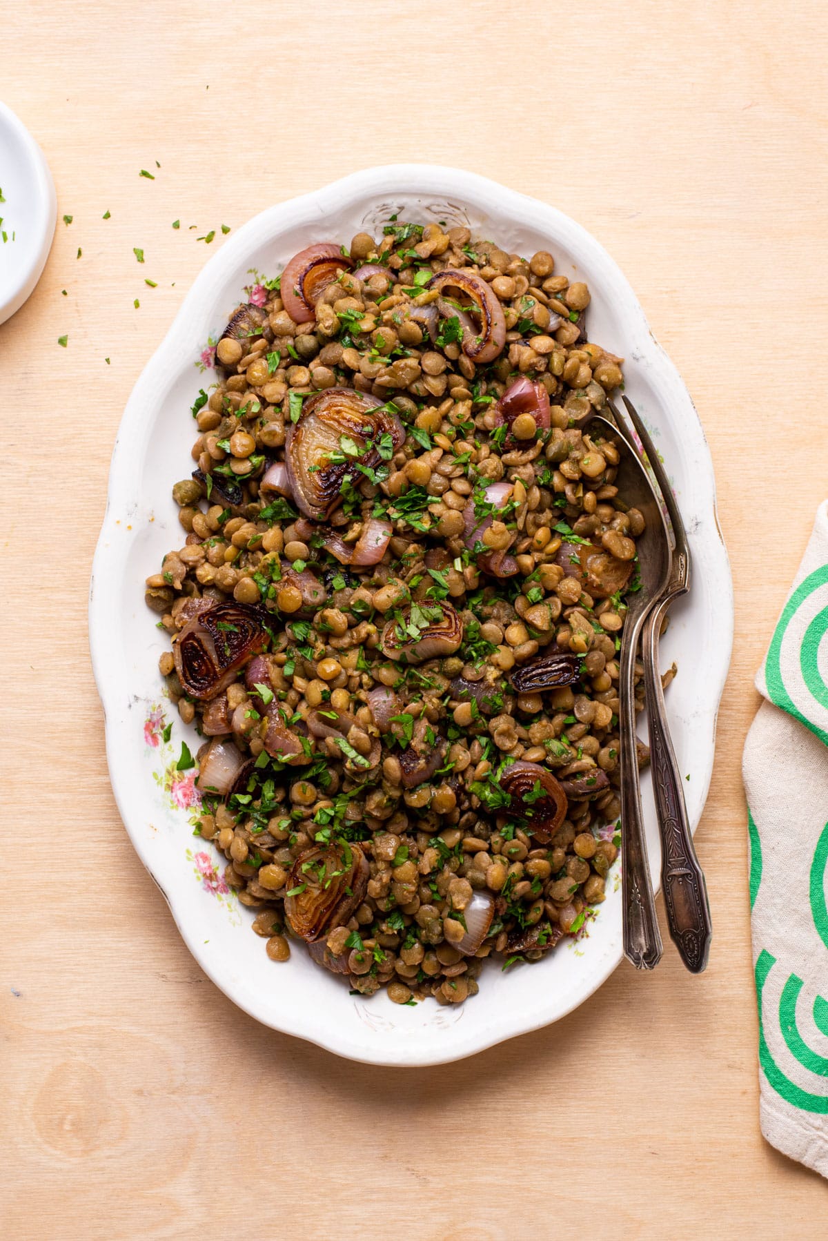 Warm lentil salad with balsamic shallots on a vintage oval platter on a wooden table.