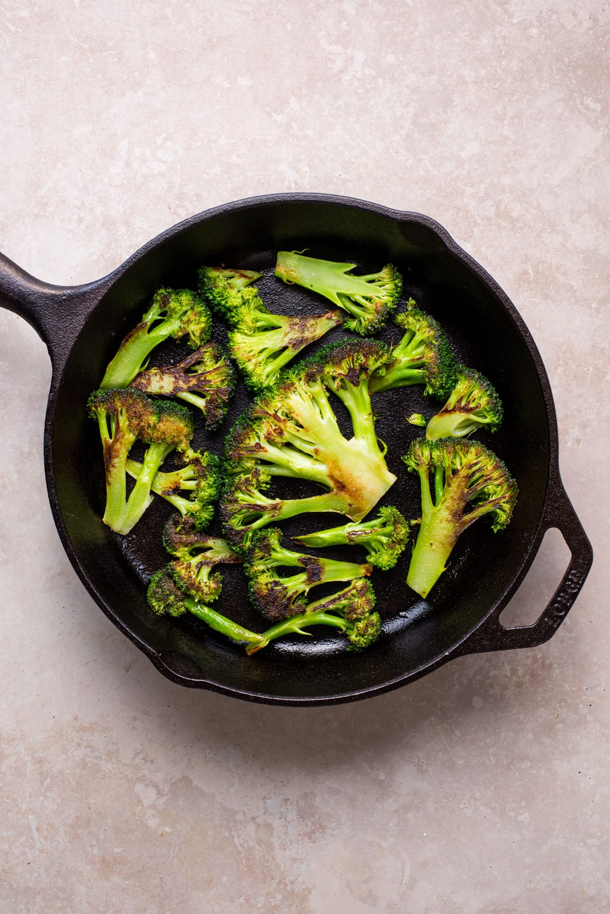 Charred broccoli pieces in a cast iron skillet.