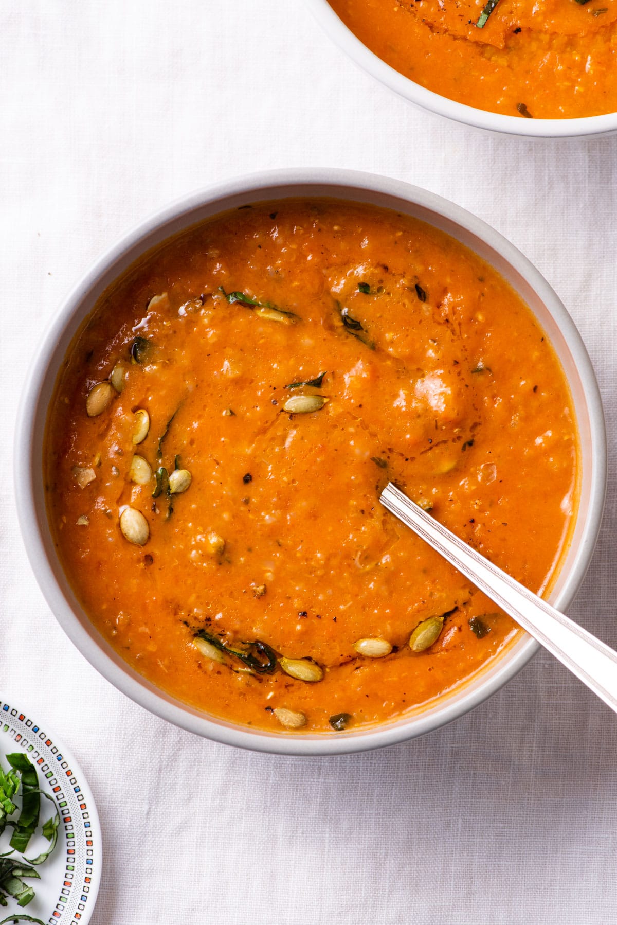 Creamy tomato soup garnished with pumpkin seeds and basil.