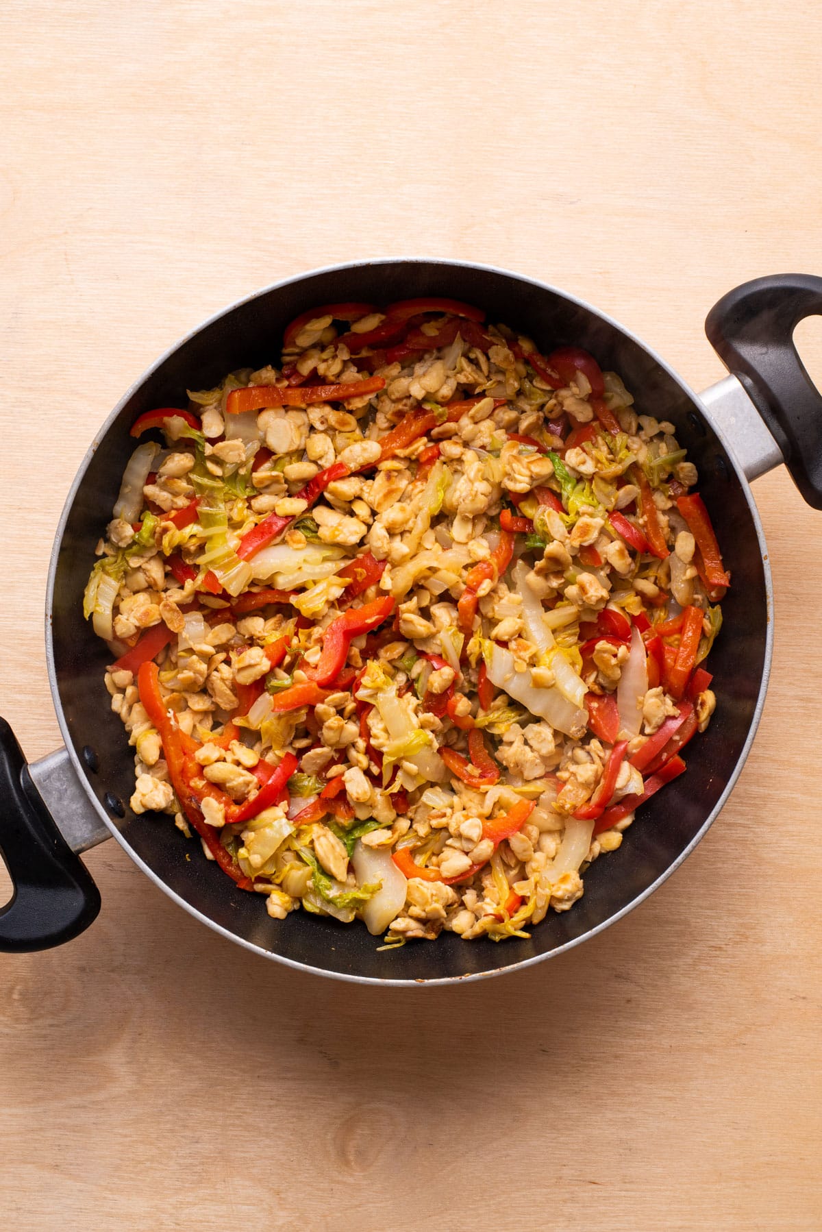 Stir-fried tempeh, bell peppers, and cabbage in a skillet.