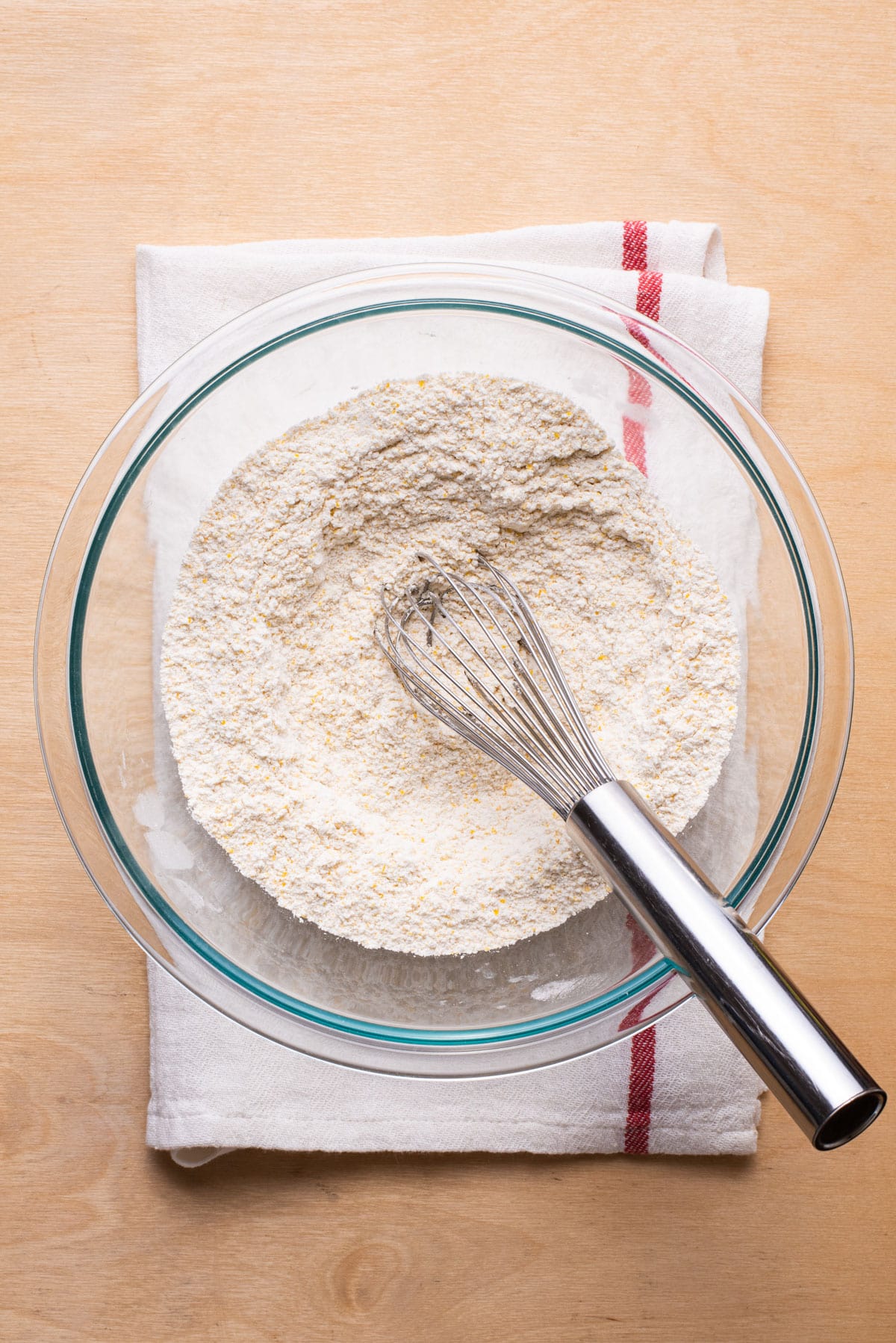 Dry ingredients for pancakes whisked together in a glass bowl.