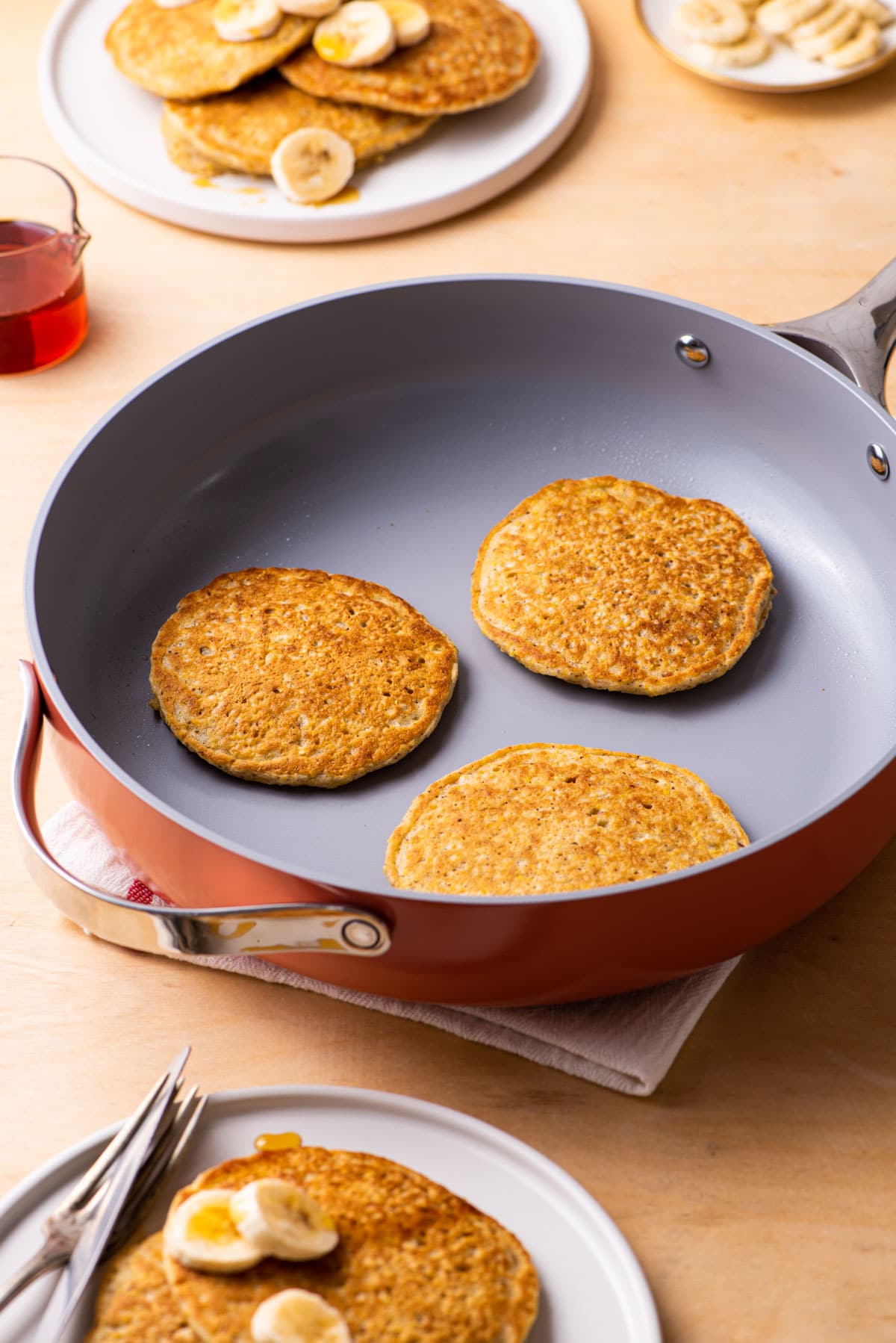 Vegan cornmeal pancakes in a pink Caraway sauté pan.