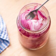No-cook quick-pickled red onions in a jar with a fork.