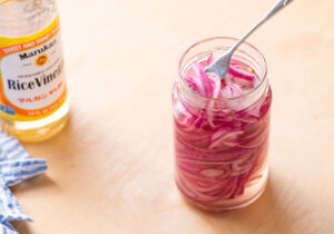 Quick-pickled red onions in a jar with a fork.