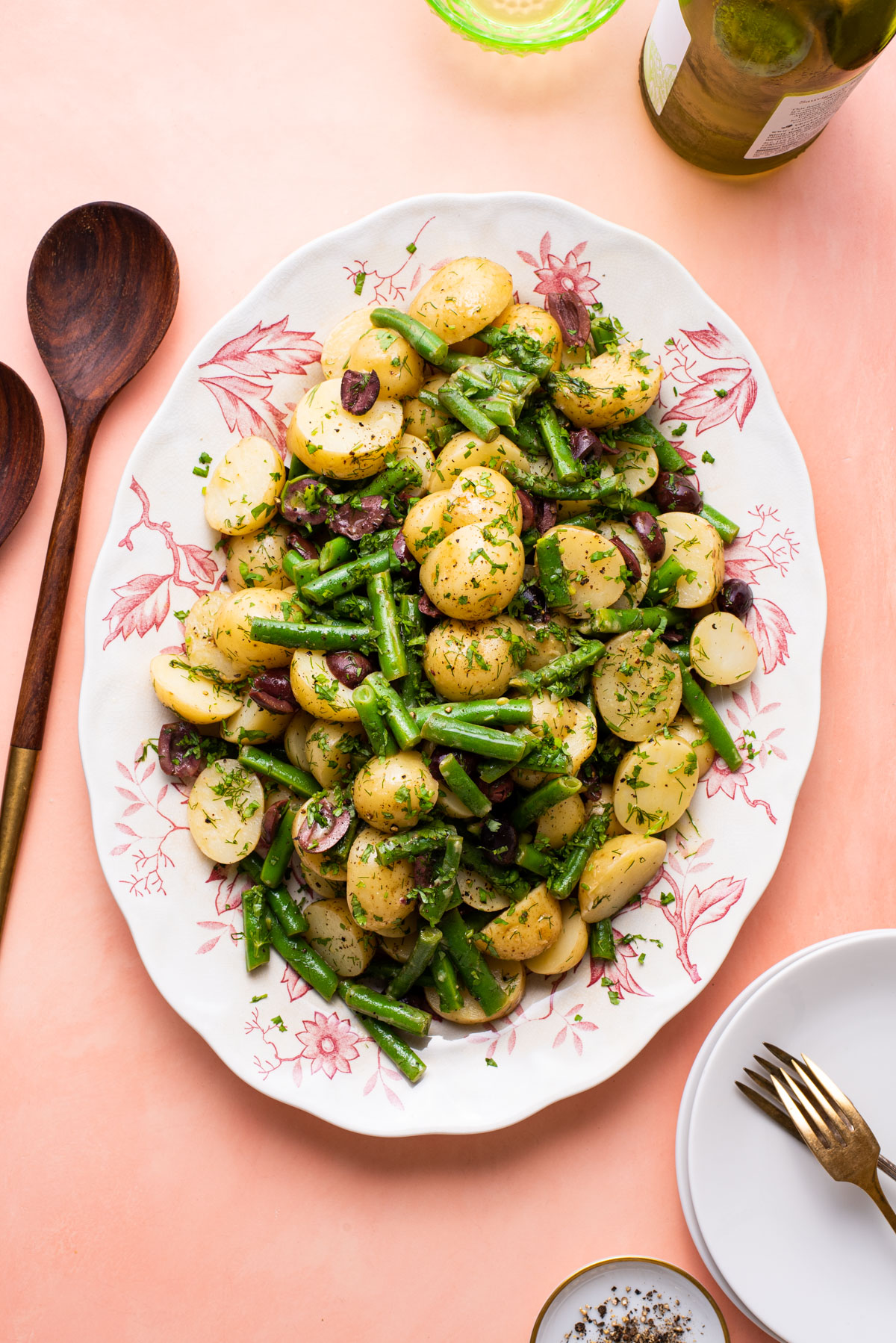 Mayo-less vegan potato salad with olives and green beans on a vintage floral platter.