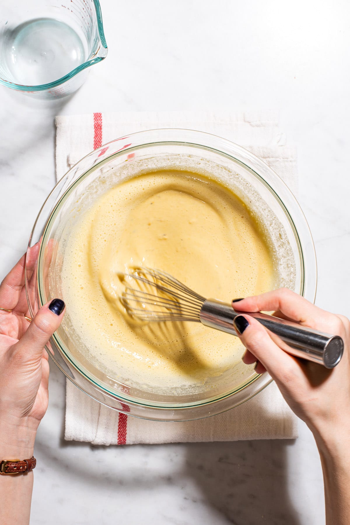 Whisking chickpea flour batter in a glass bowl.