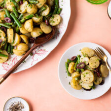 Mayo-less vegan potato salad with olives and green beans on a vintage floral platter and on a small white plate.