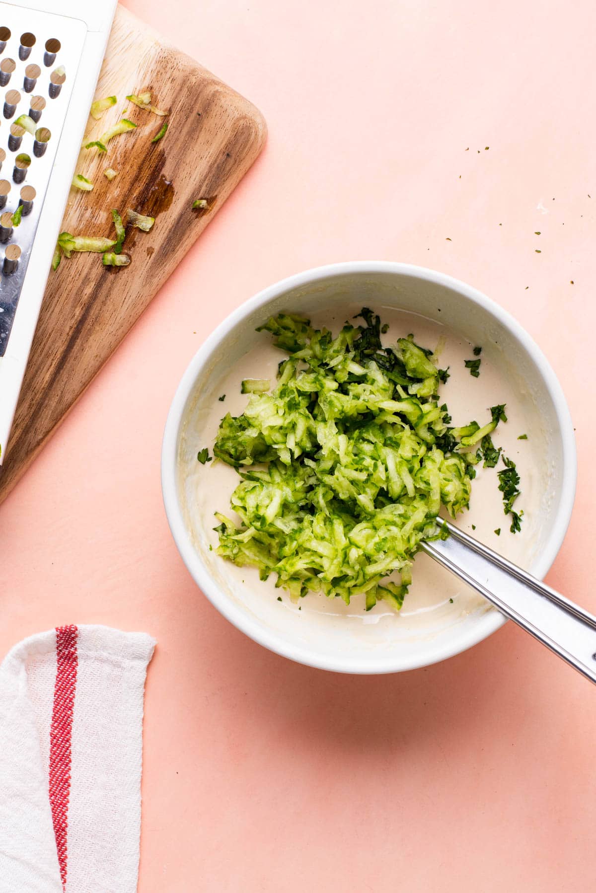 Grated cucumber and fresh herbs in a bowl with tahini sauce.
