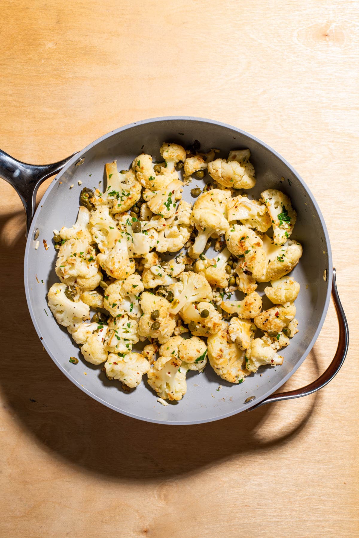 Sauteed cauliflower with lemon and capers in a skillet.